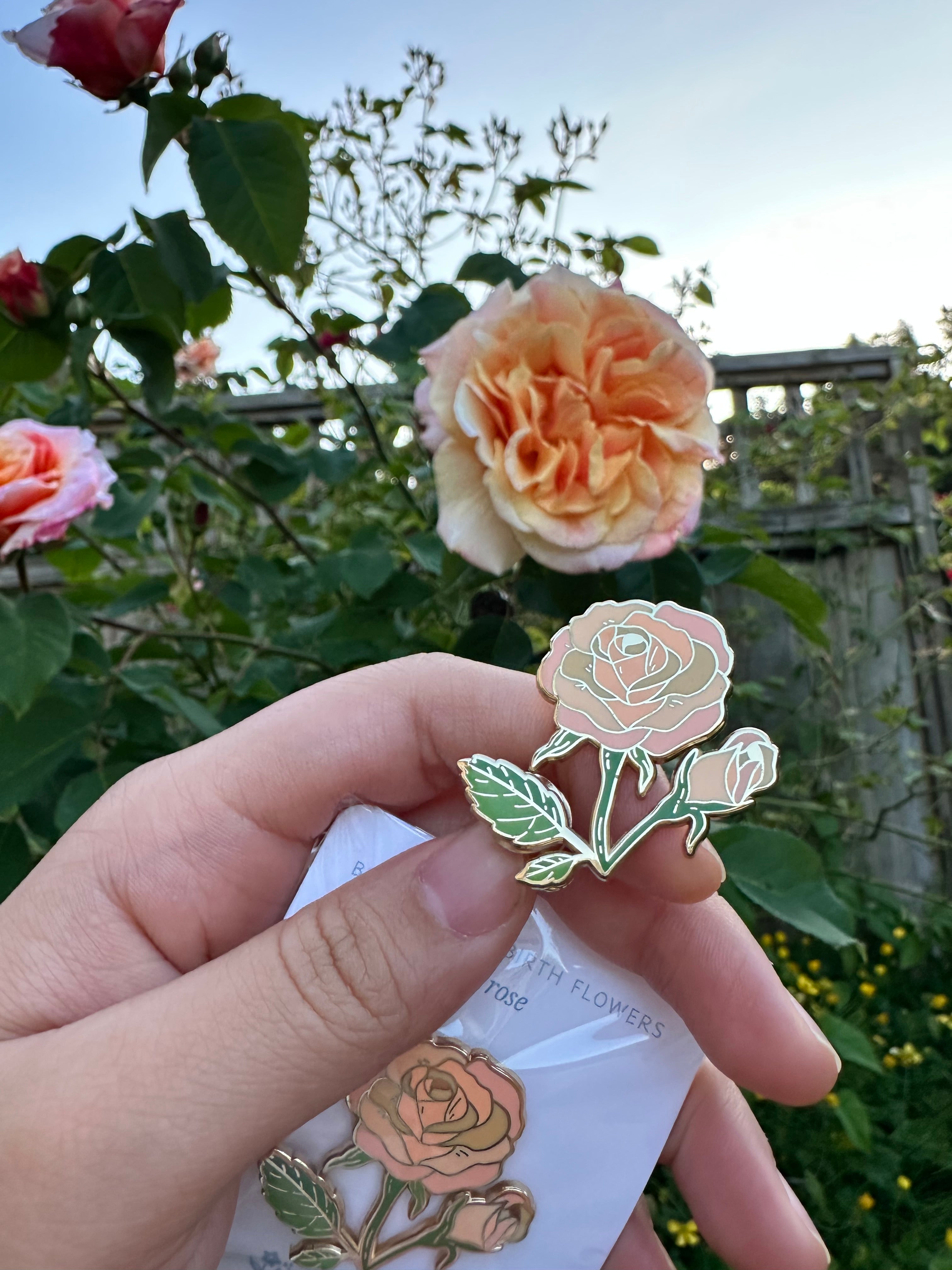 Hand holding a floral pin with flowers in the background